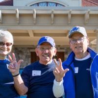 3 class of 1967 Alumni stand in front of Alumni House and Visitor's Center and anchor up